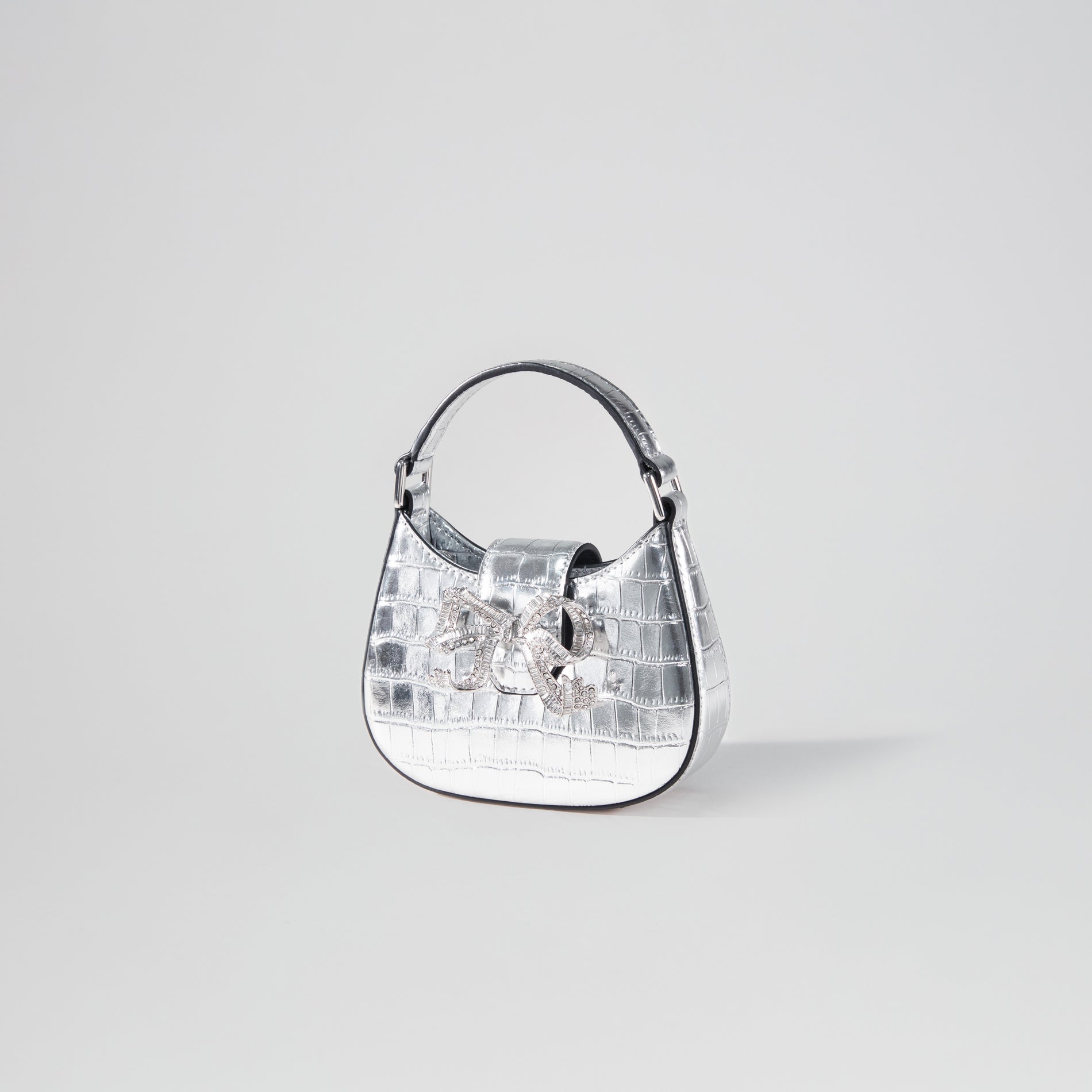 Side view of a woman wearing the Silver Croc Crescent Bow Micro Bag