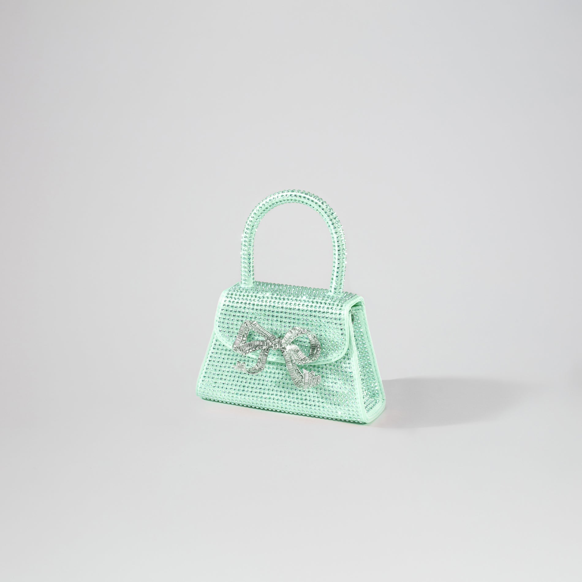 Side view of a woman wearing the Green Rhinestone Micro Bow Bag