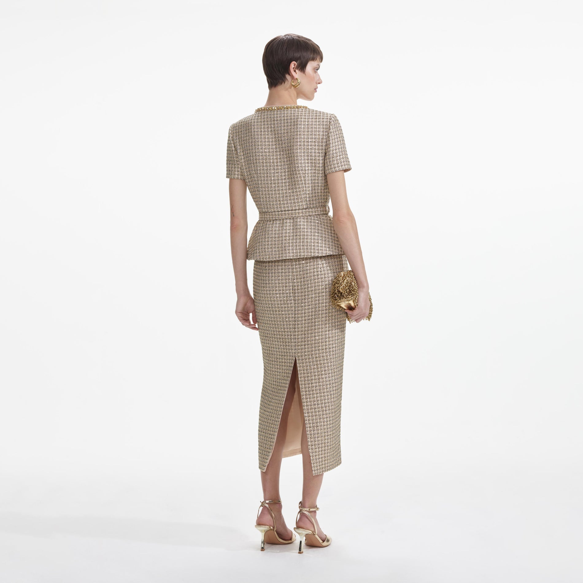 Back view of a woman wearing the Gold Boucle Peplum Top
