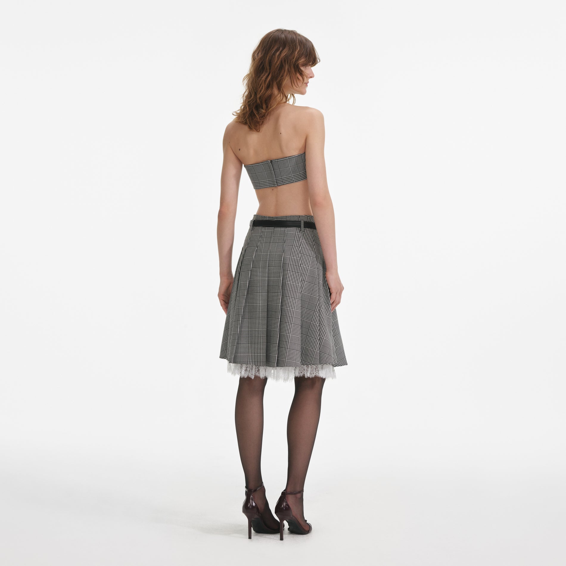 Back view of a woman wearing the Prince Of Wales Check Pleated Midi Skirt