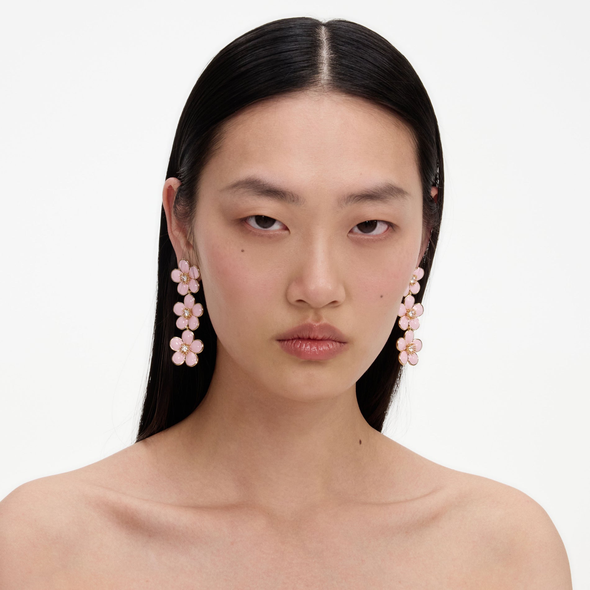 A close up of a woman wearing the Pink Enamel Flower Tiered Earrings