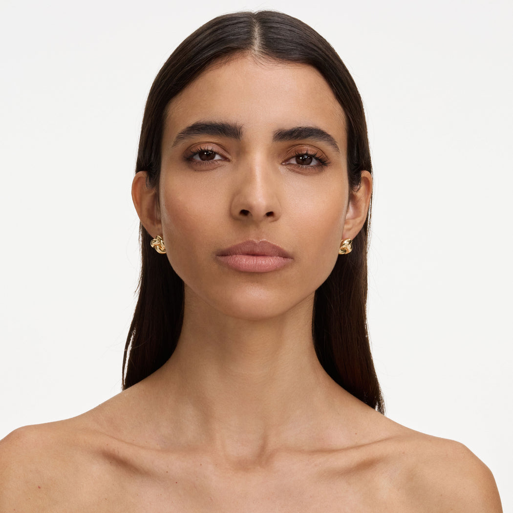 A close up of a woman wearing the Gold Small Knot Earrings