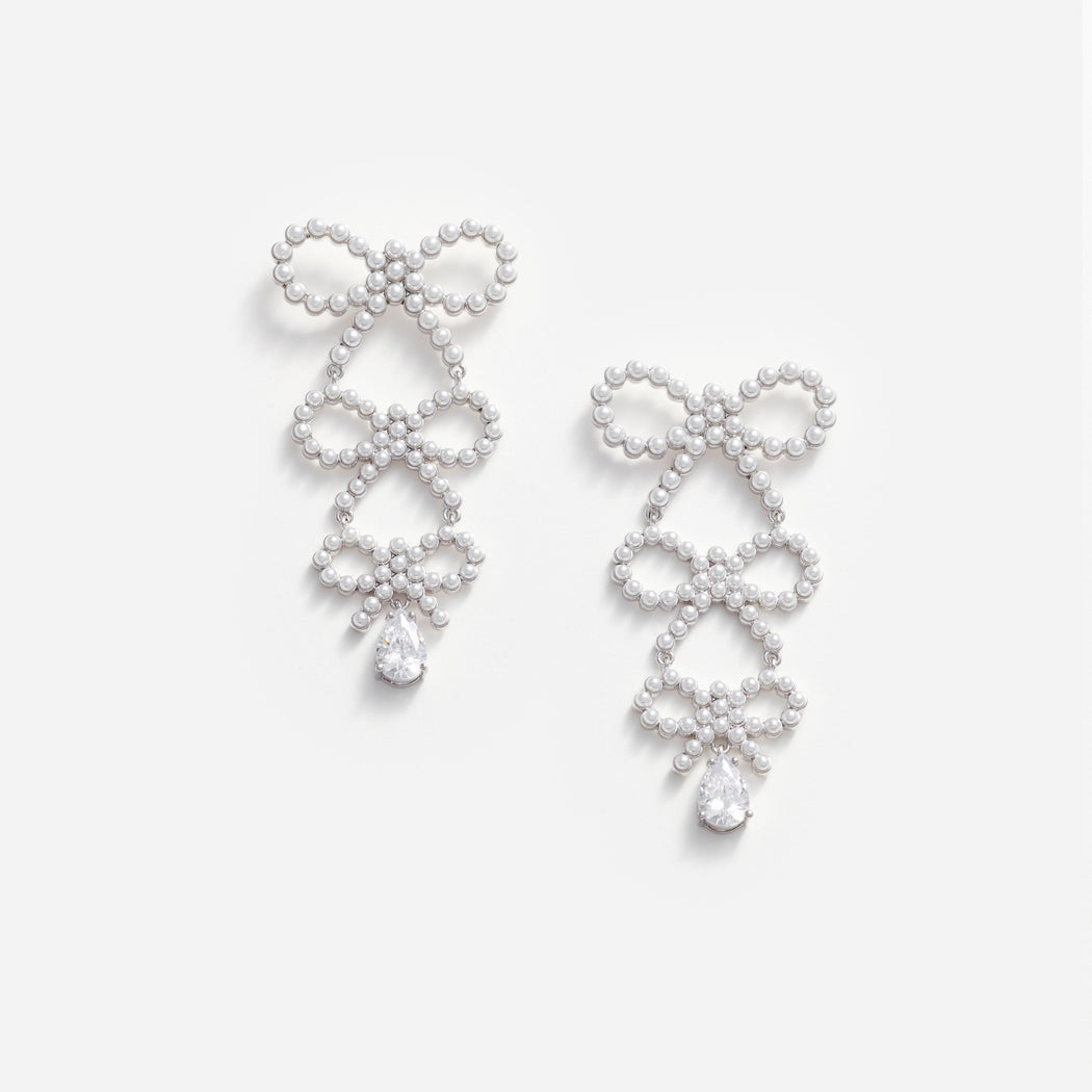 Front view of a woman wearing the Tiered Pearl Bow Earrings