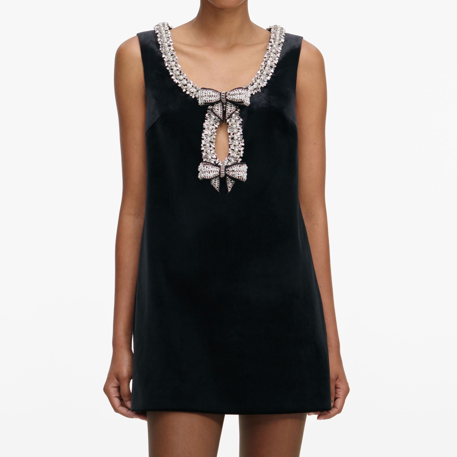 A close up of a woman wearing the Black Velvet Bow Mini Dress