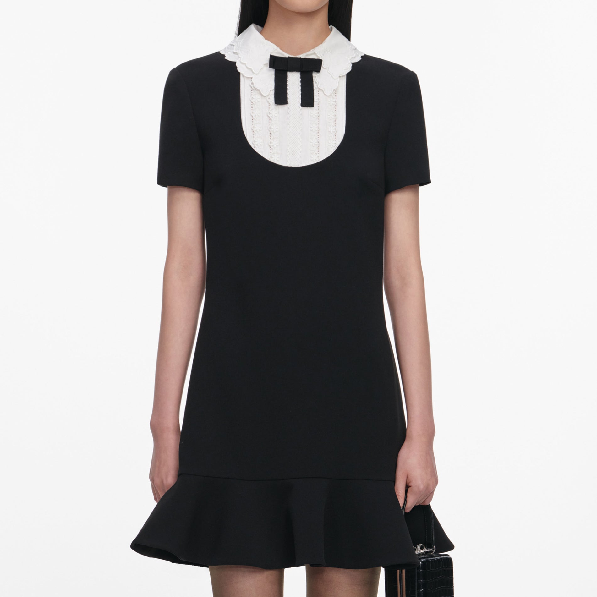 A close up of a woman wearing the Black Crepe Lace Bib Mini Dress