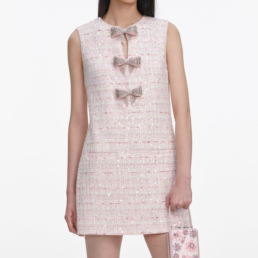 A close up of a woman wearing the Pink Sequin Boucle Bow Mini Dress