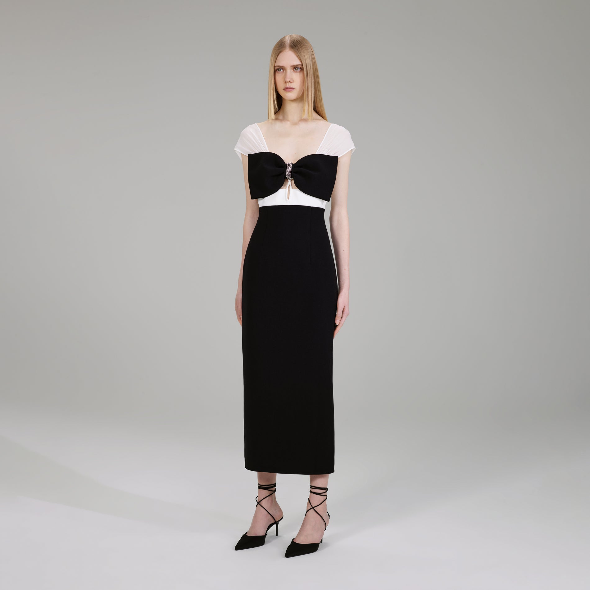A woman wearing the Black And White Crepe Bow Midi Dress