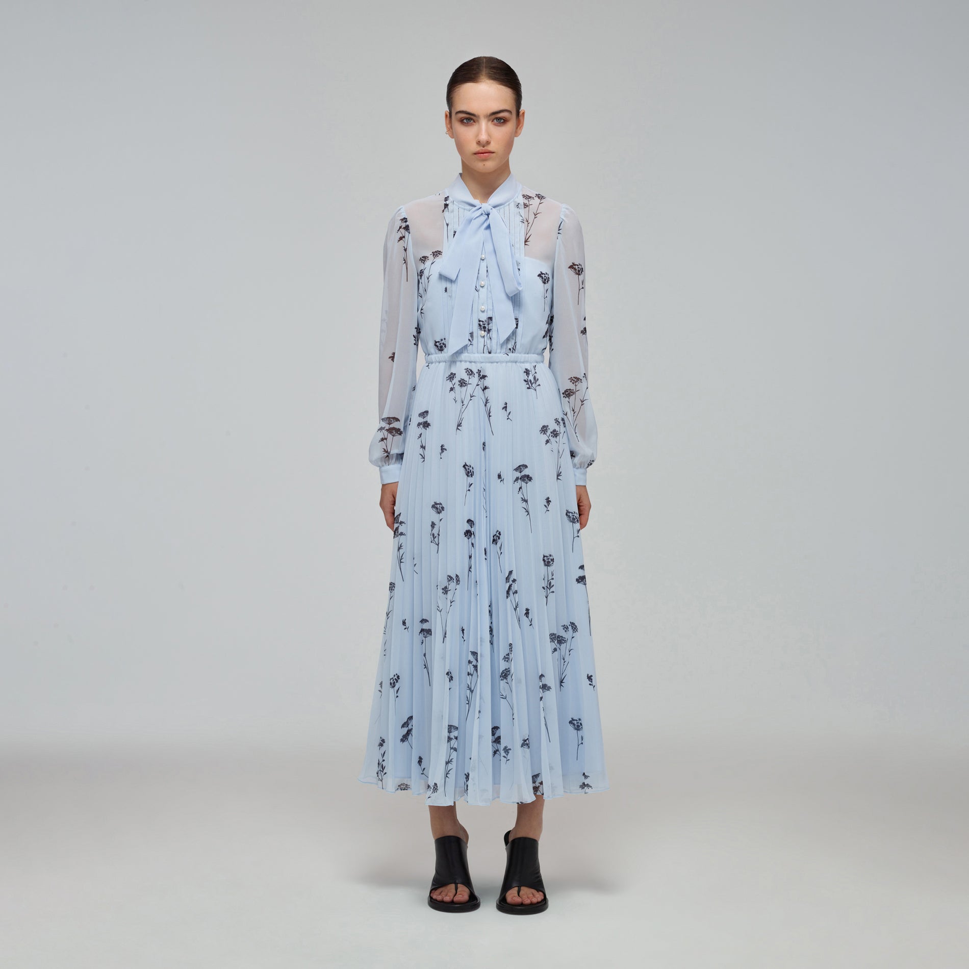 A woman wearing the Blue Floral Silhouette Chiffon Midi Dress