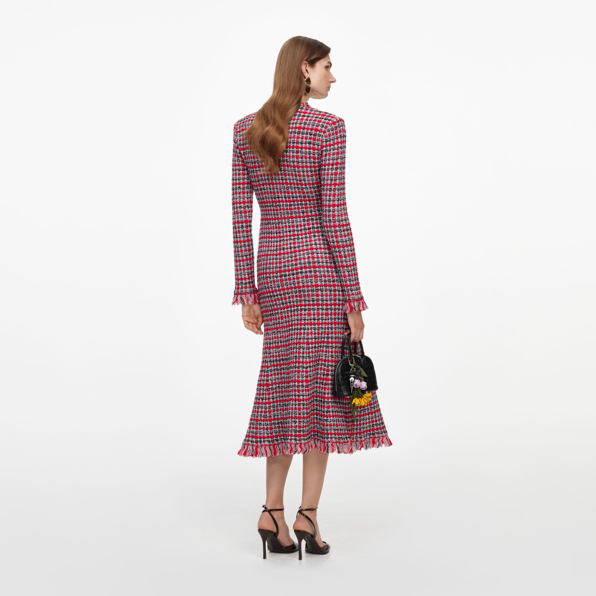 Woman in red, black, and white plaid dress with fringe hem, black heels, and black handbag with flowers