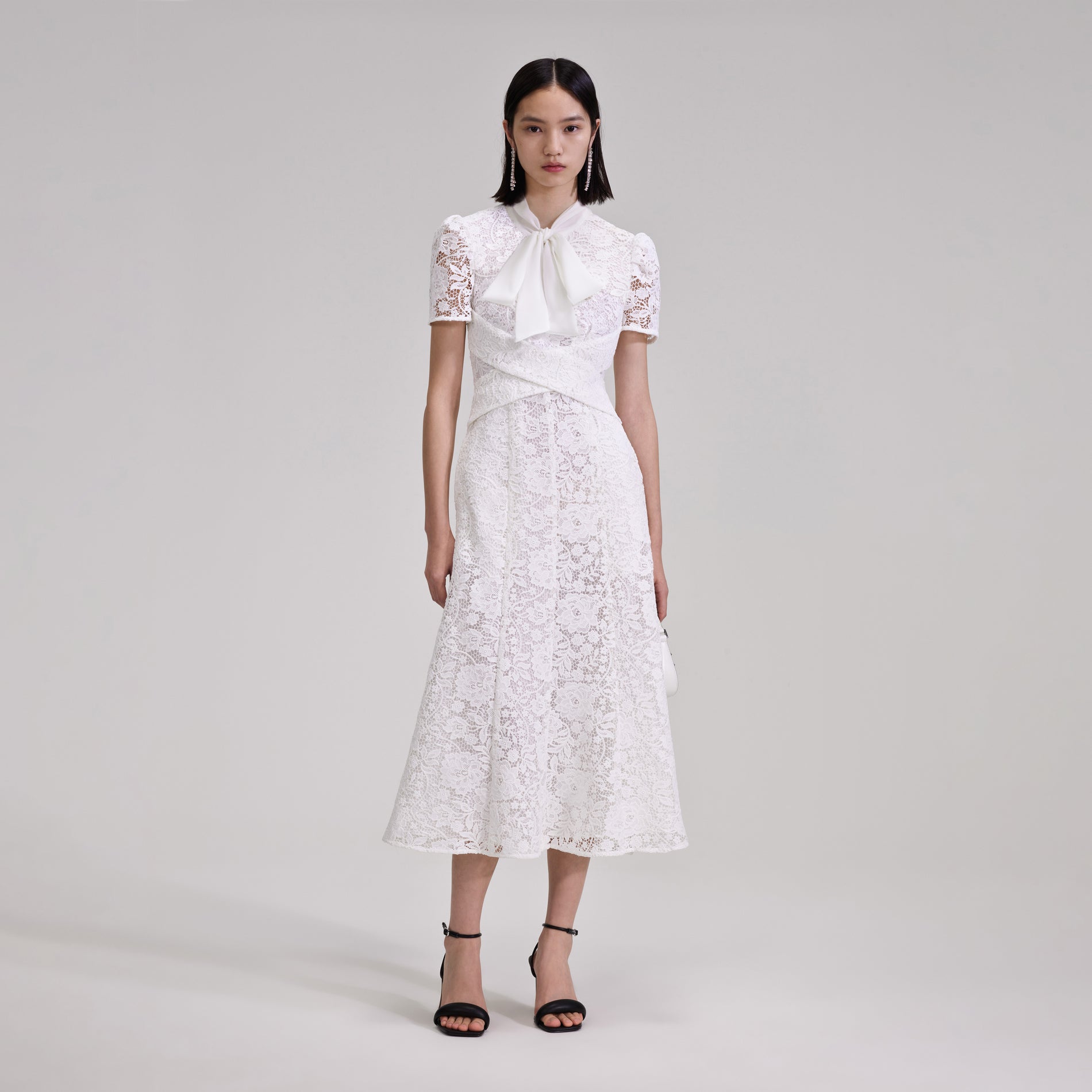 A woman wearing the White Cord Lace Crossover Midi Dress