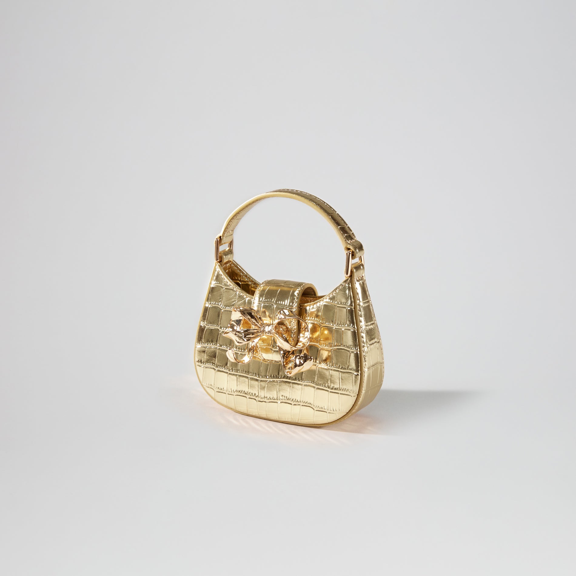 Side view of a woman wearing the Gold Croc Crescent Bow Micro Bag