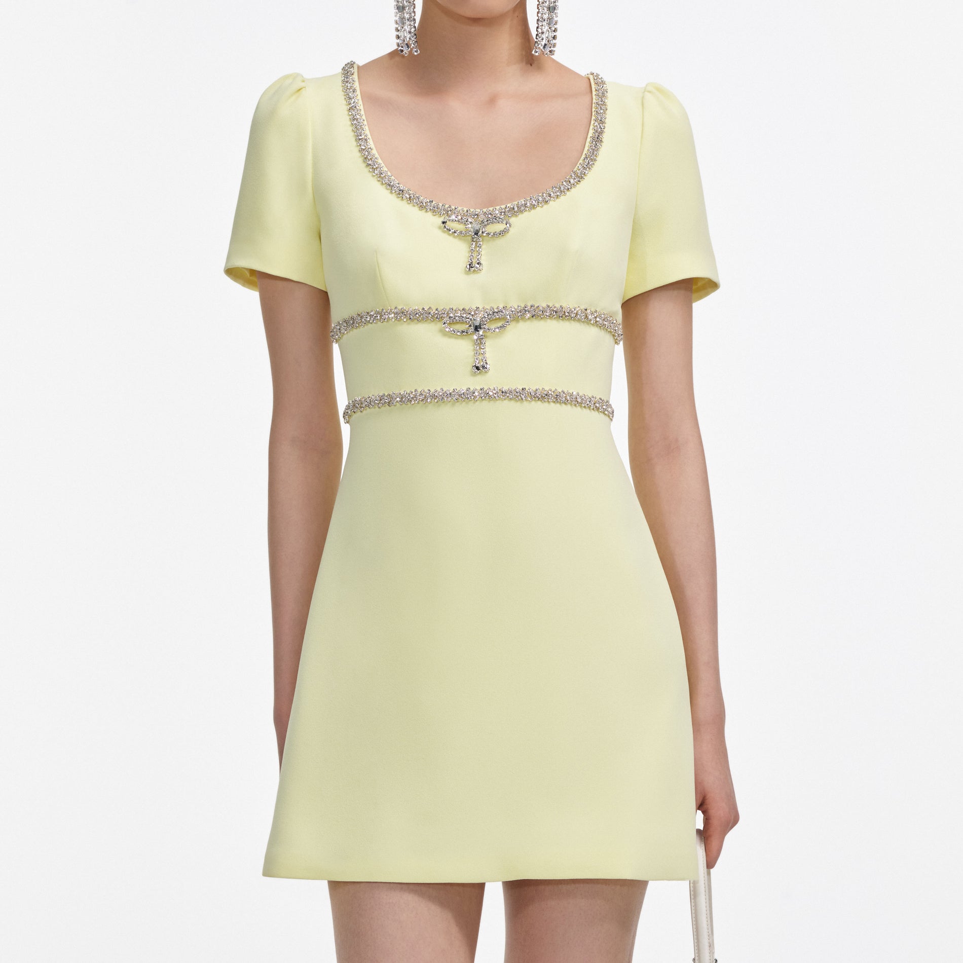 A close up of a woman wearing the Yellow Crepe Crystal Trim Mini Dress