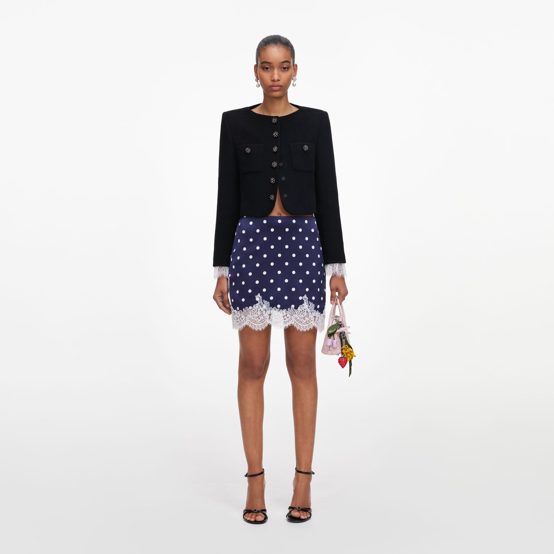 Front view of a woman wearing the Navy Polka Dot Satin Mini Skirt