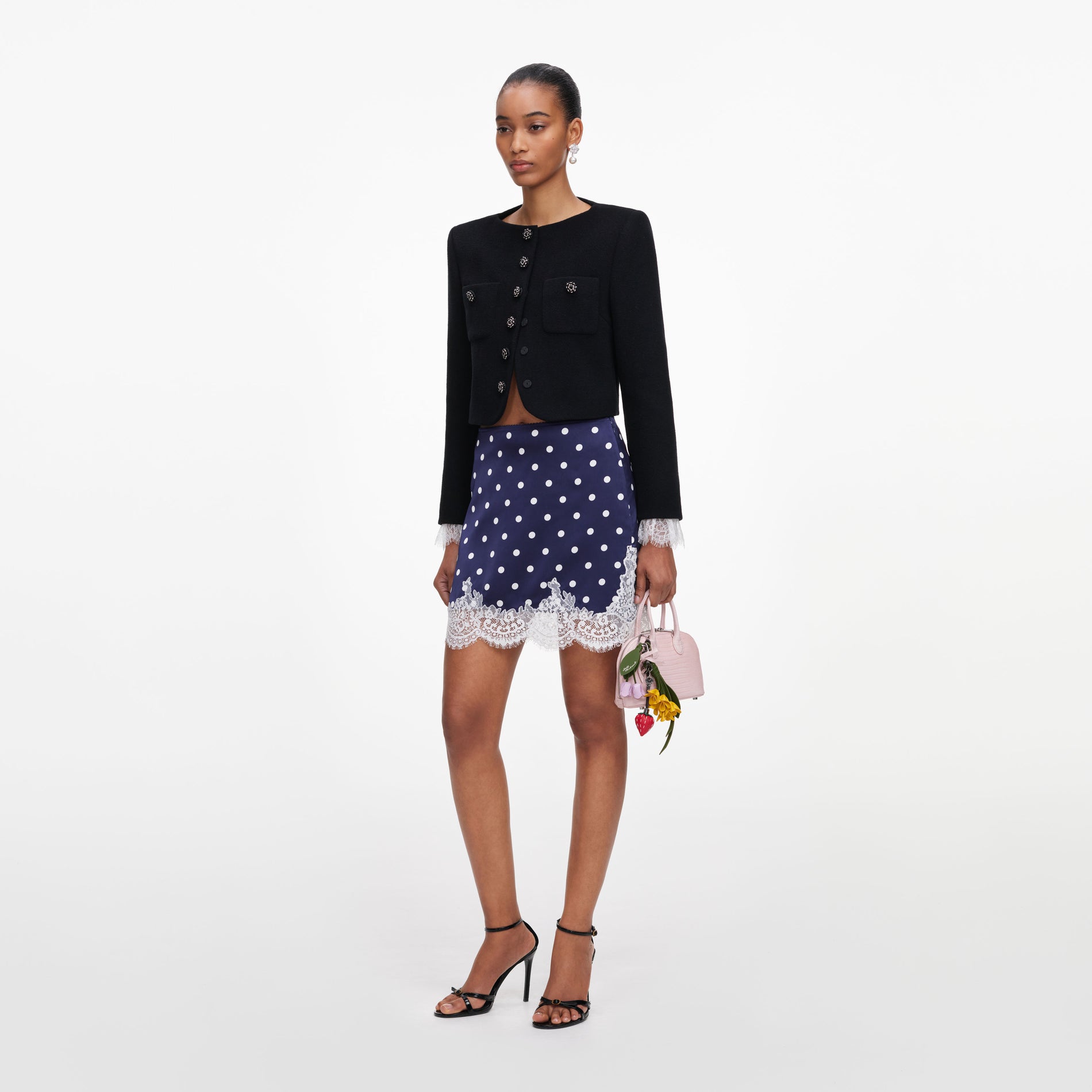 Side view of a woman wearing the Navy Polka Dot Satin Mini Skirt
