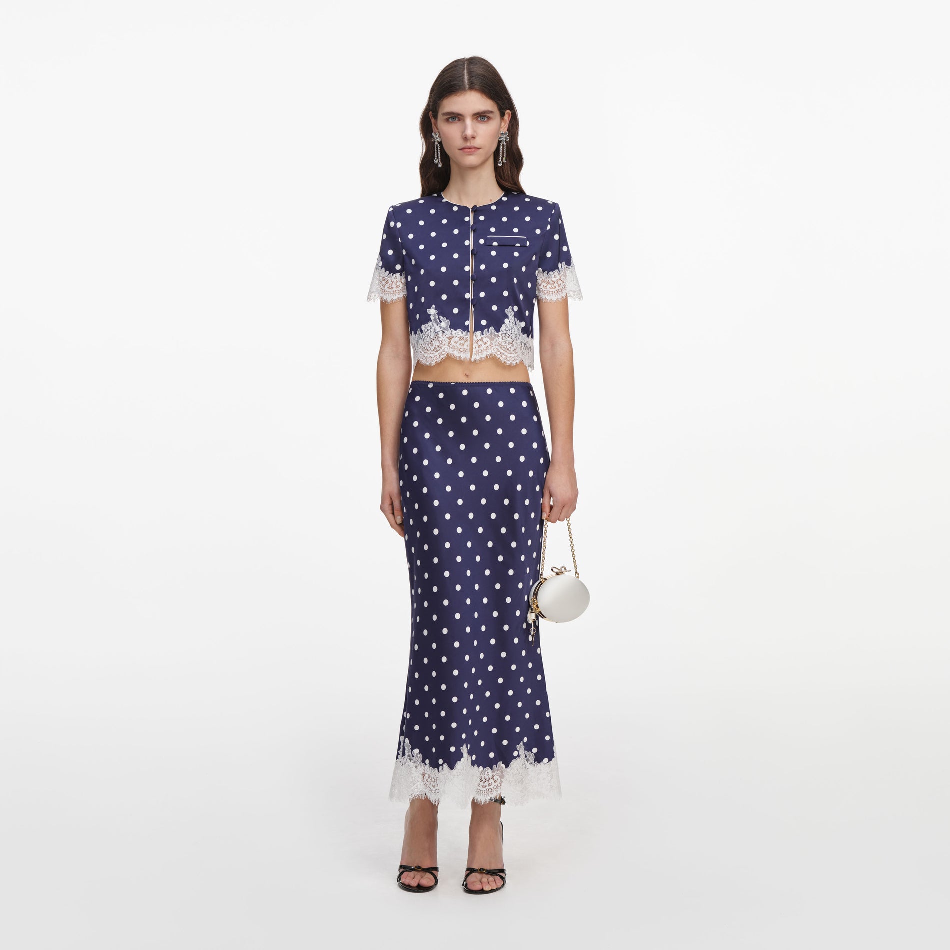Front view of a woman wearing the Navy Polka Dot Satin Midi Skirt