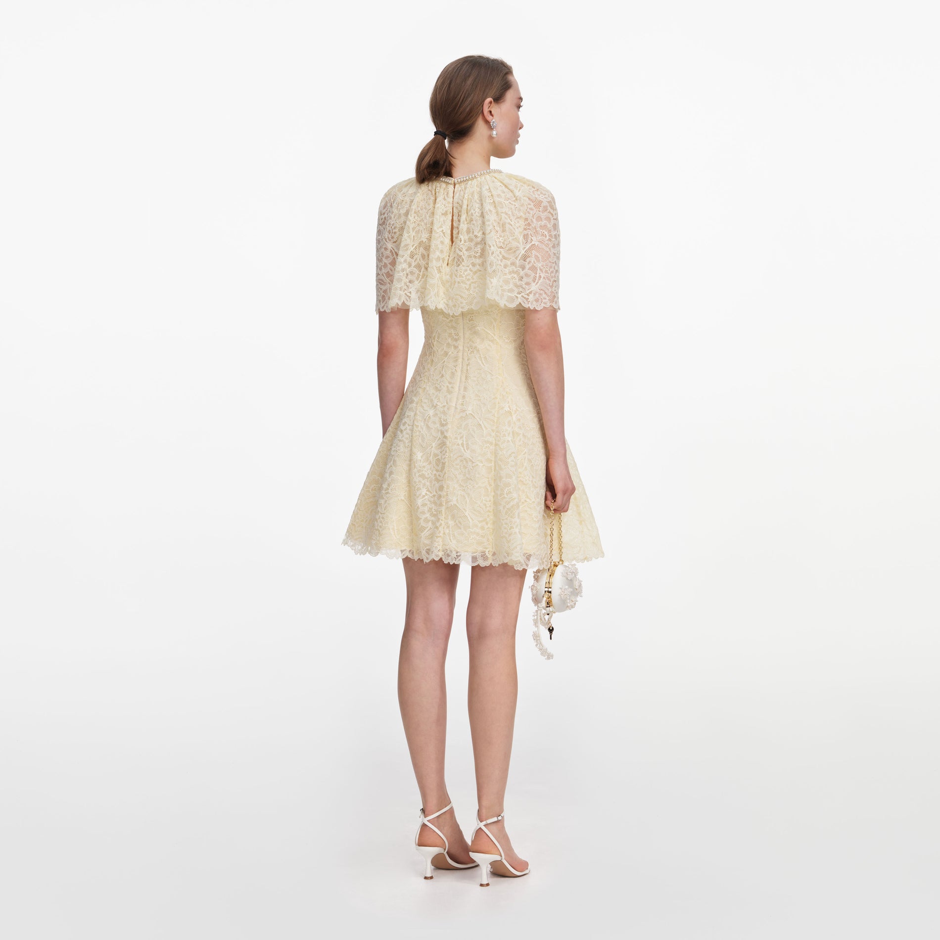 Back view of a woman wearing the Yellow Lace Cape Mini Dress