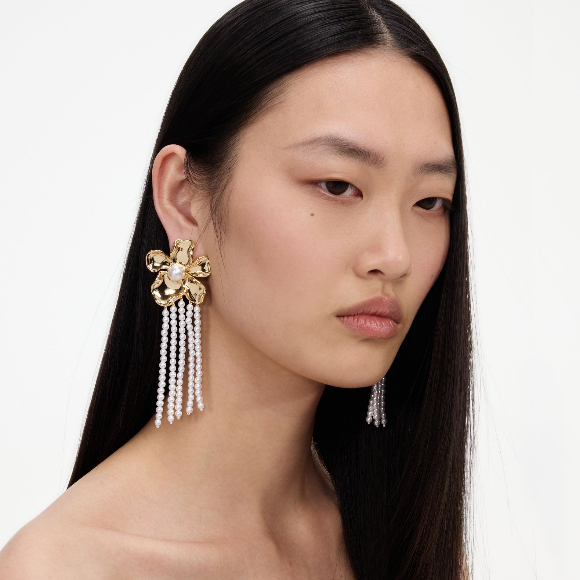 A close up of a woman wearing the Gold Flower Pearl Dangle Earrings