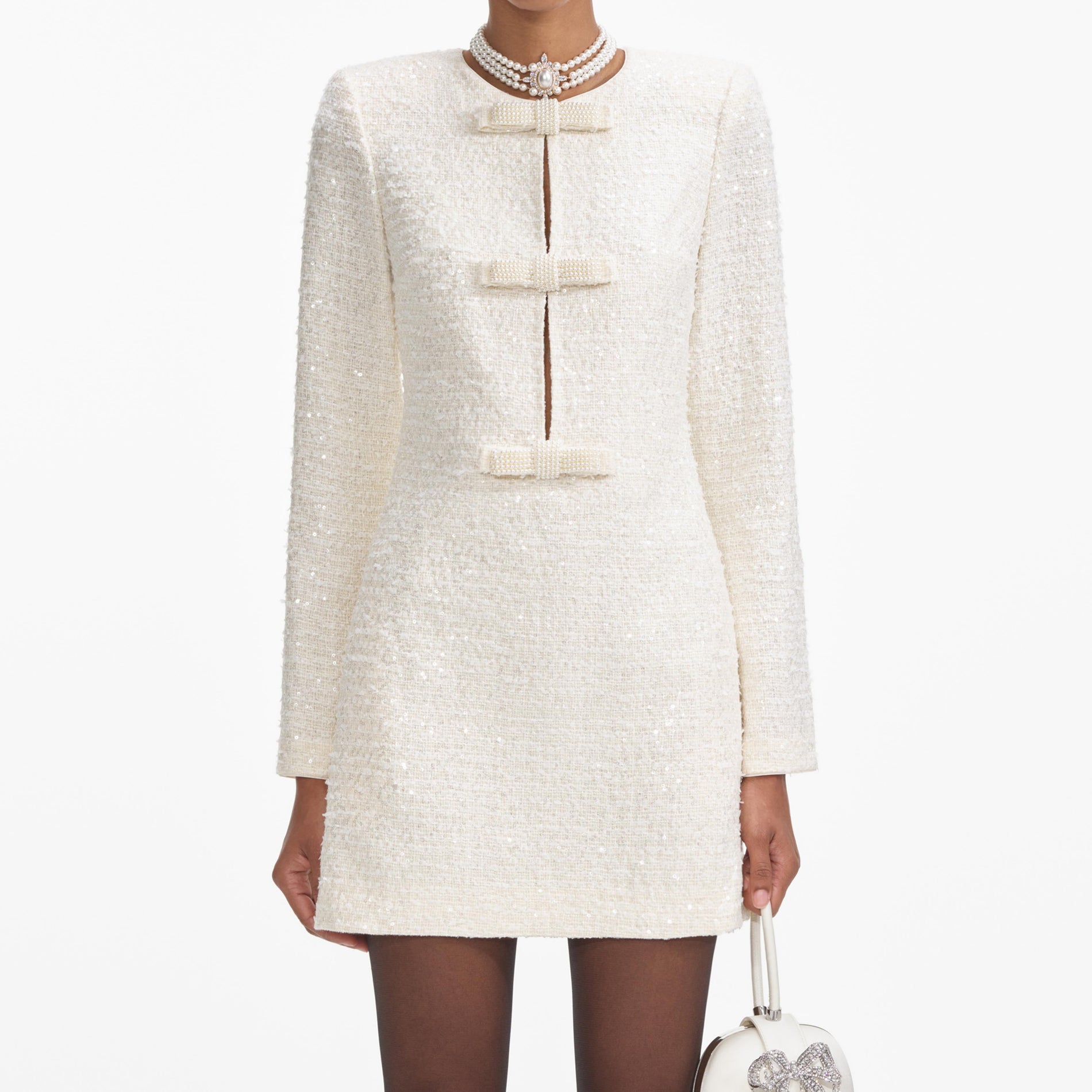 A close up of a woman wearing the Cream Boucle Diamante Bow Mini Dress