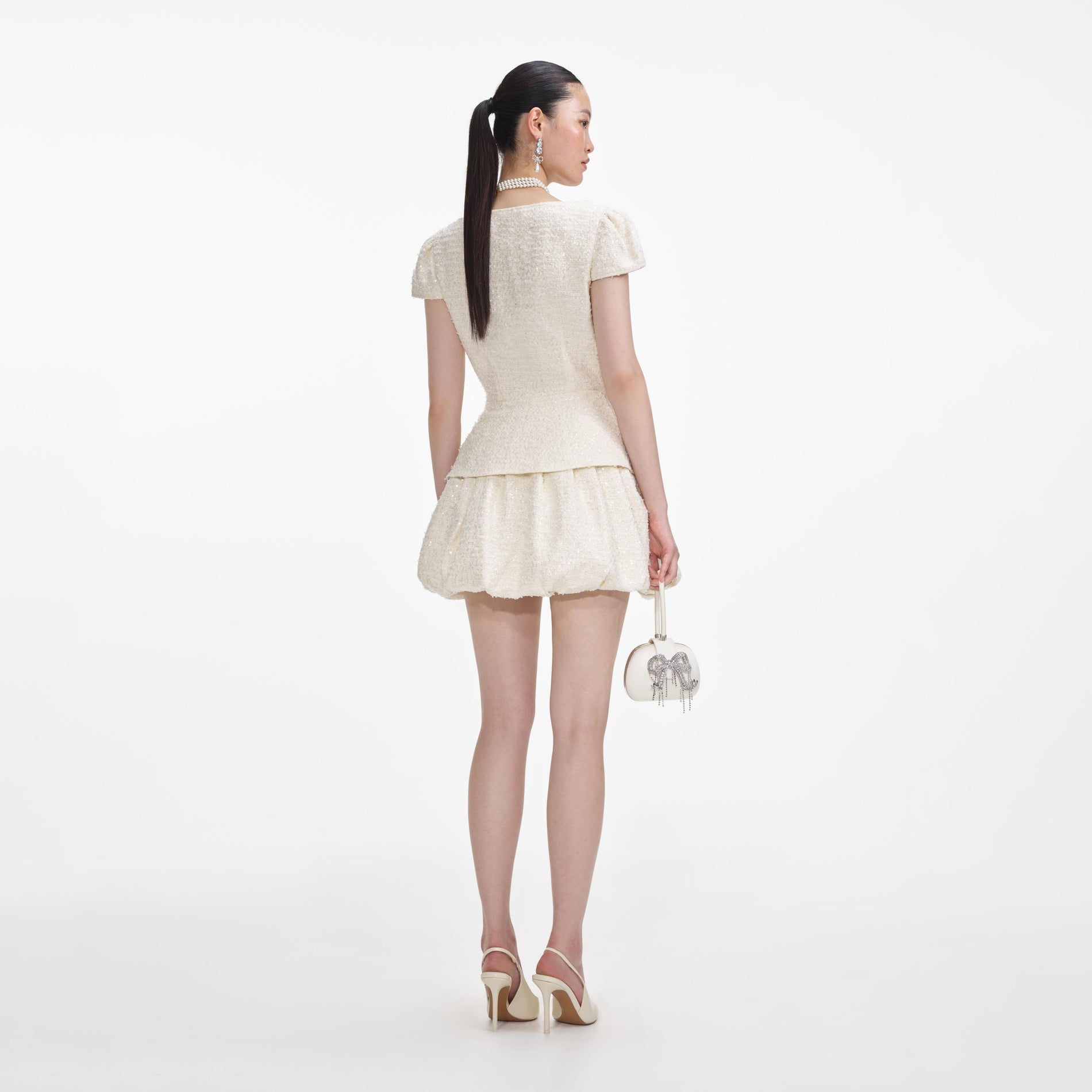 Back view of a woman wearing the Cream Boucle Bow Detail Mini Dress