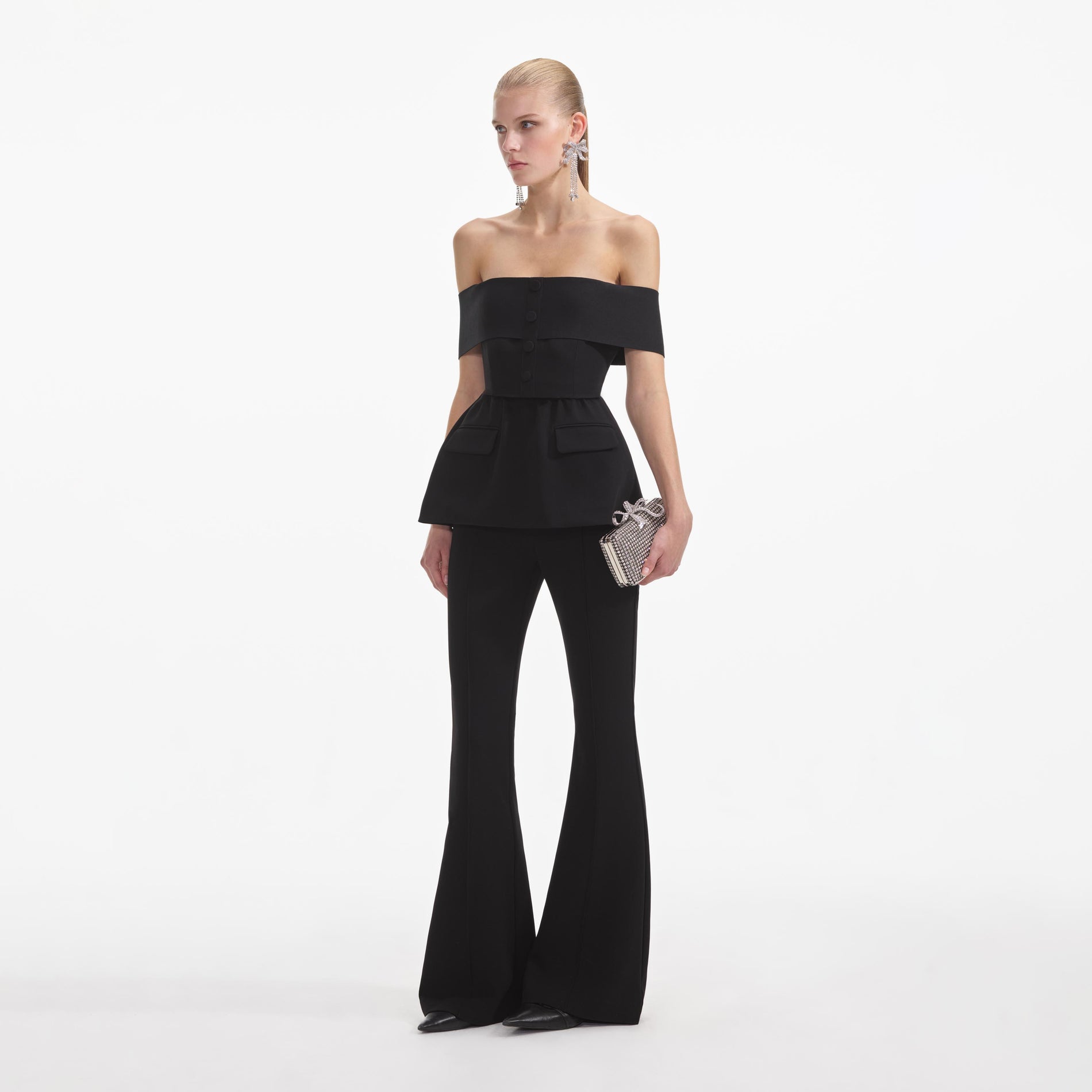 Side view of a woman wearing the Black Crepe Off Shoulder Jumpsuit
