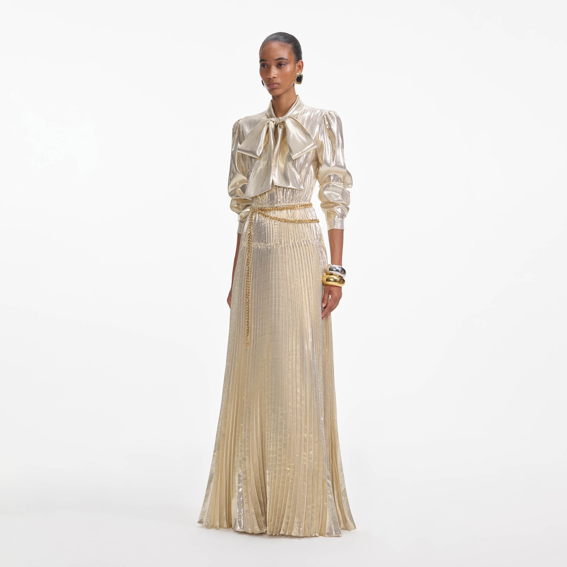 Side view of a woman wearing the Gold Metallic Pussy Bow Maxi Dress