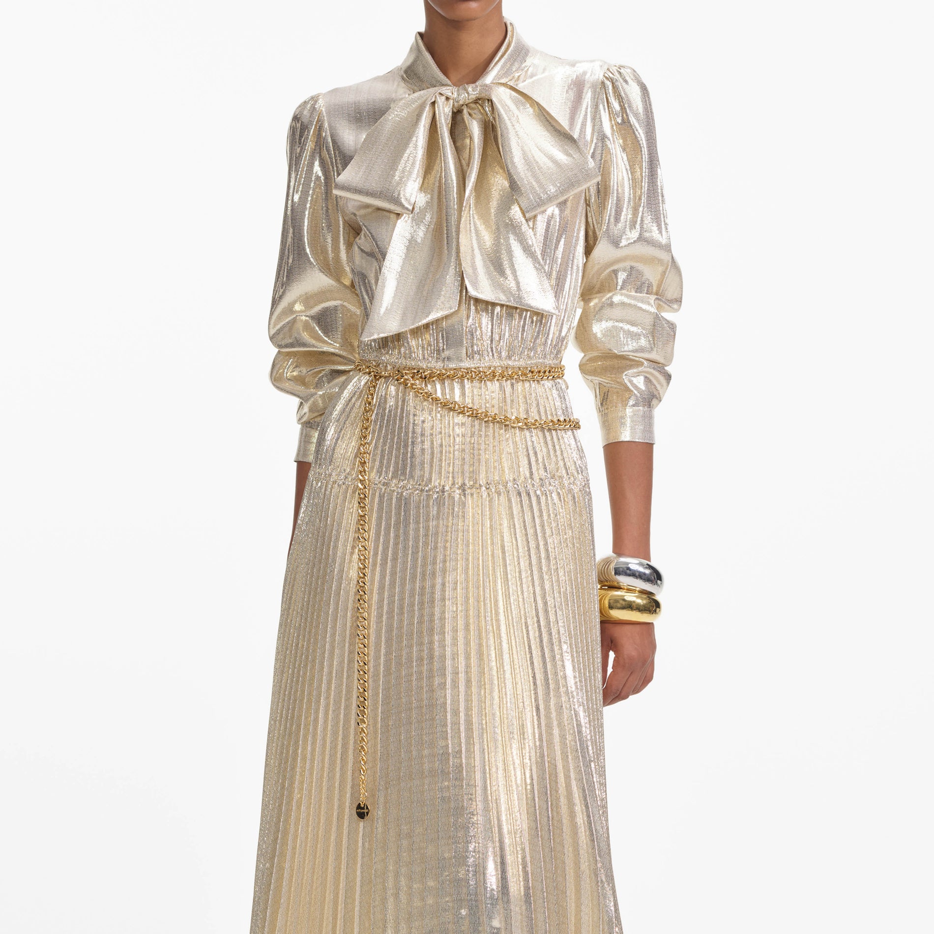 A close up of a woman wearing the Gold Metallic Pussy Bow Maxi Dress