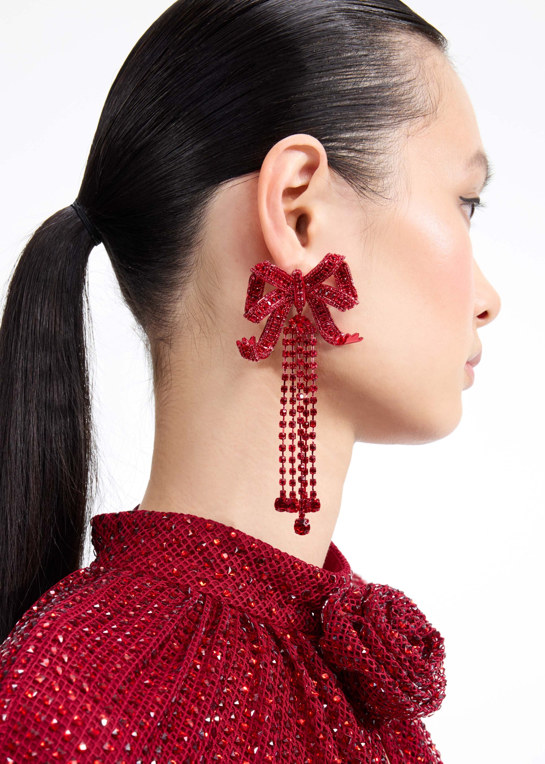 A close up of a woman wearing the Red Bow Diamante Earrings