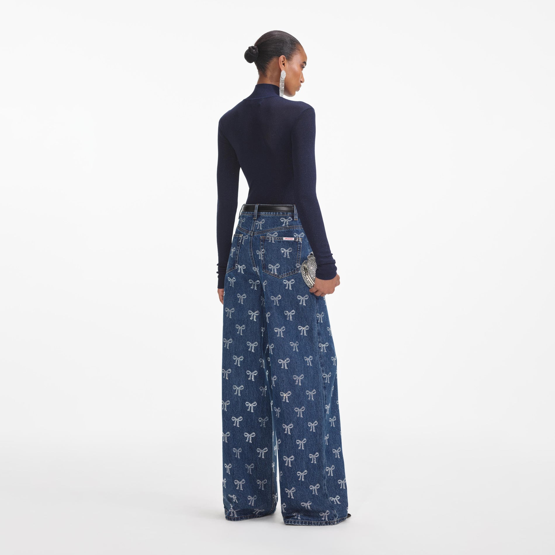 Back view of a woman wearing the Rhinestone Bow Denim Jeans