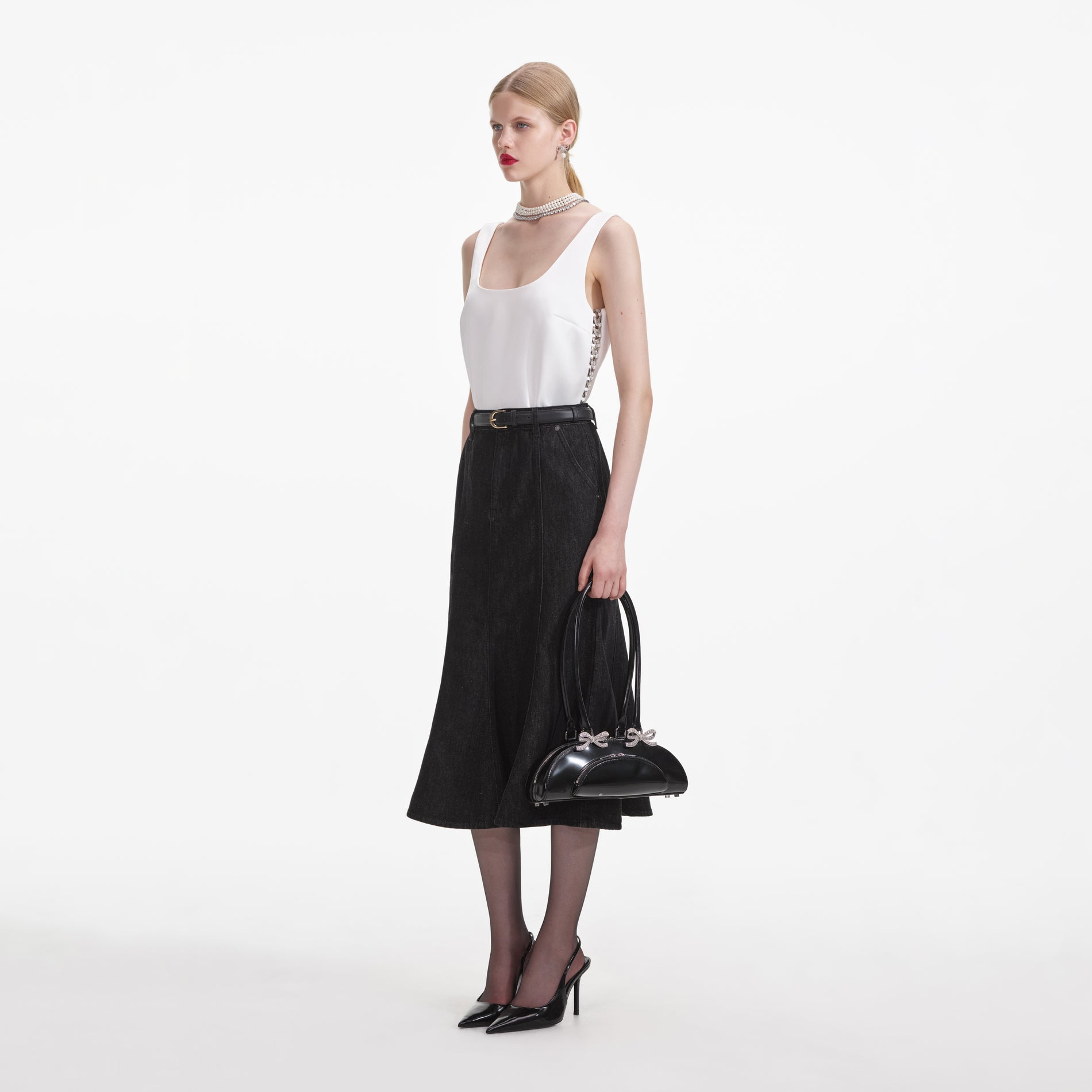 Side view of a woman wearing the Black Flared Denim Midi Skirt