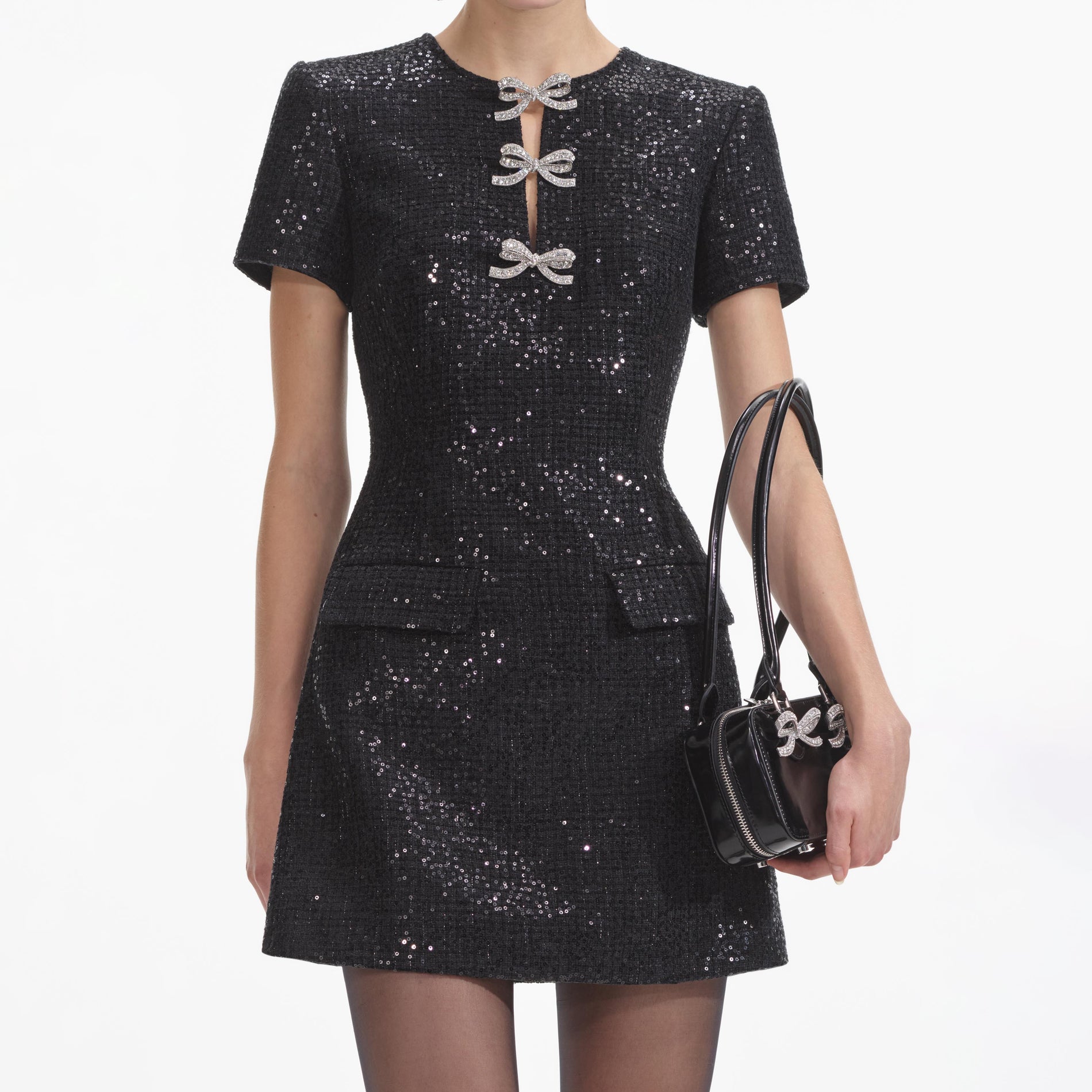 A close up of a woman wearing the Black Boucle Bow Mini Dress