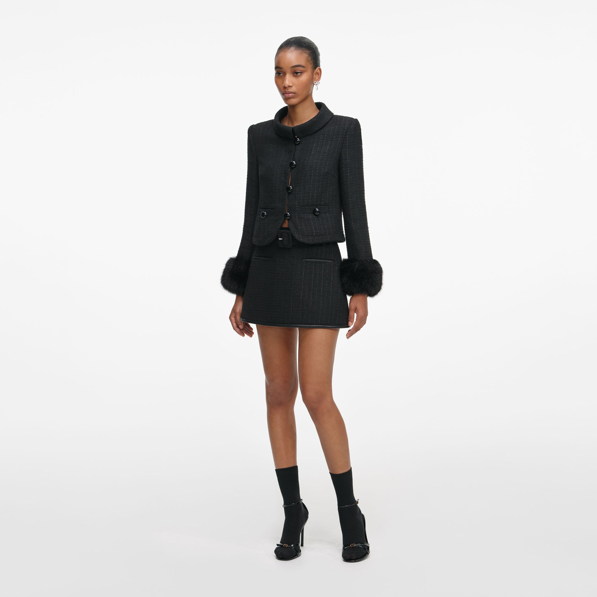 Side view of a woman wearing the Black Boucle Faux Fur Cuff Jacket