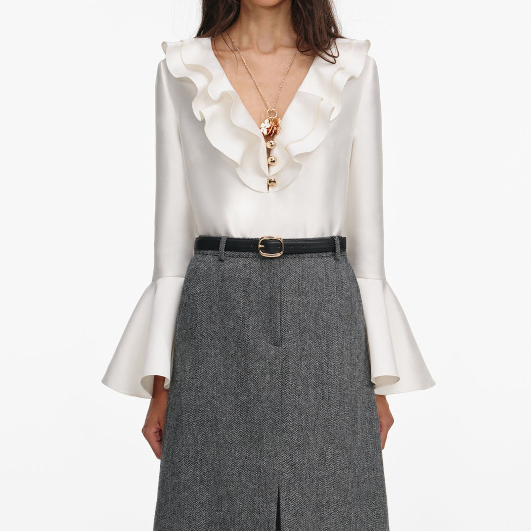 A close up of a woman wearing the Cream Taffeta Ruffle Top