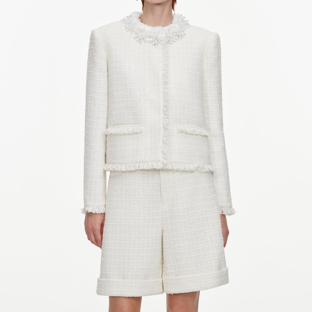 A close up of a woman wearing the Cream Sequin Boucle Pearl Trim Jacket