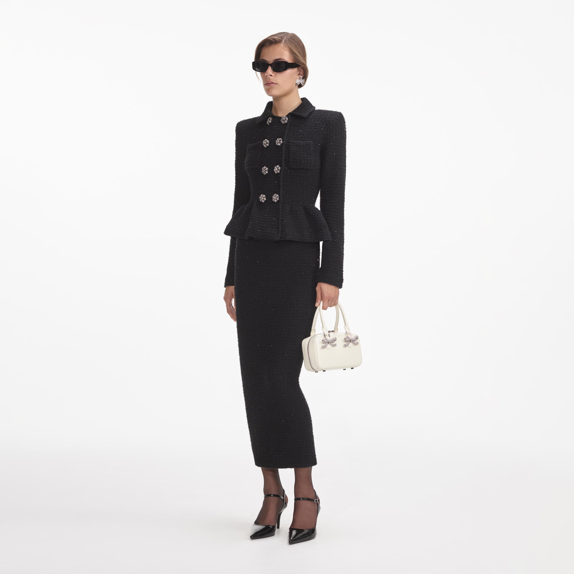 Side view of a woman wearing the Black Textured Knit Peplum Midi Dress