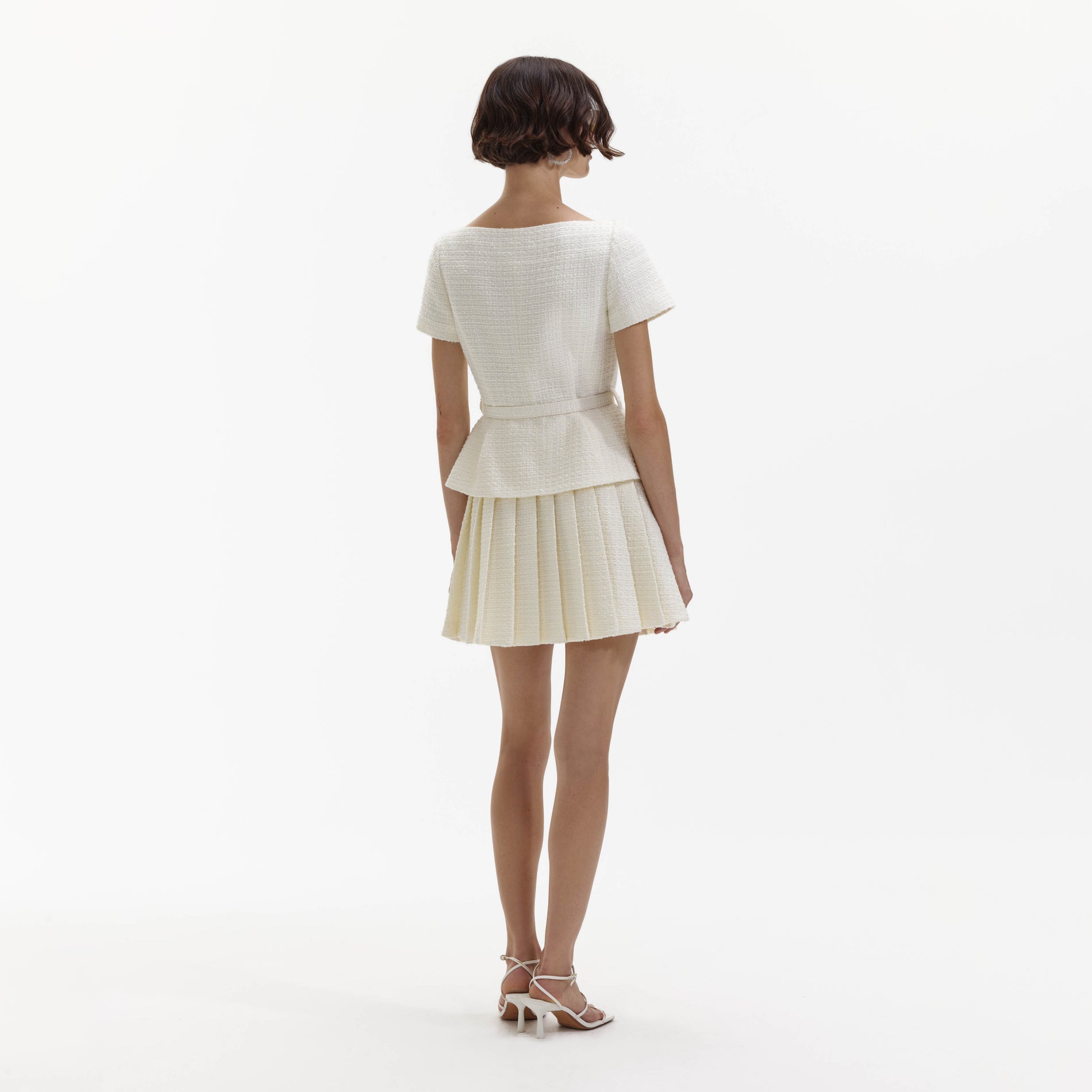 Back view of a woman wearing the Cream Boucle Pleated Mini Dress