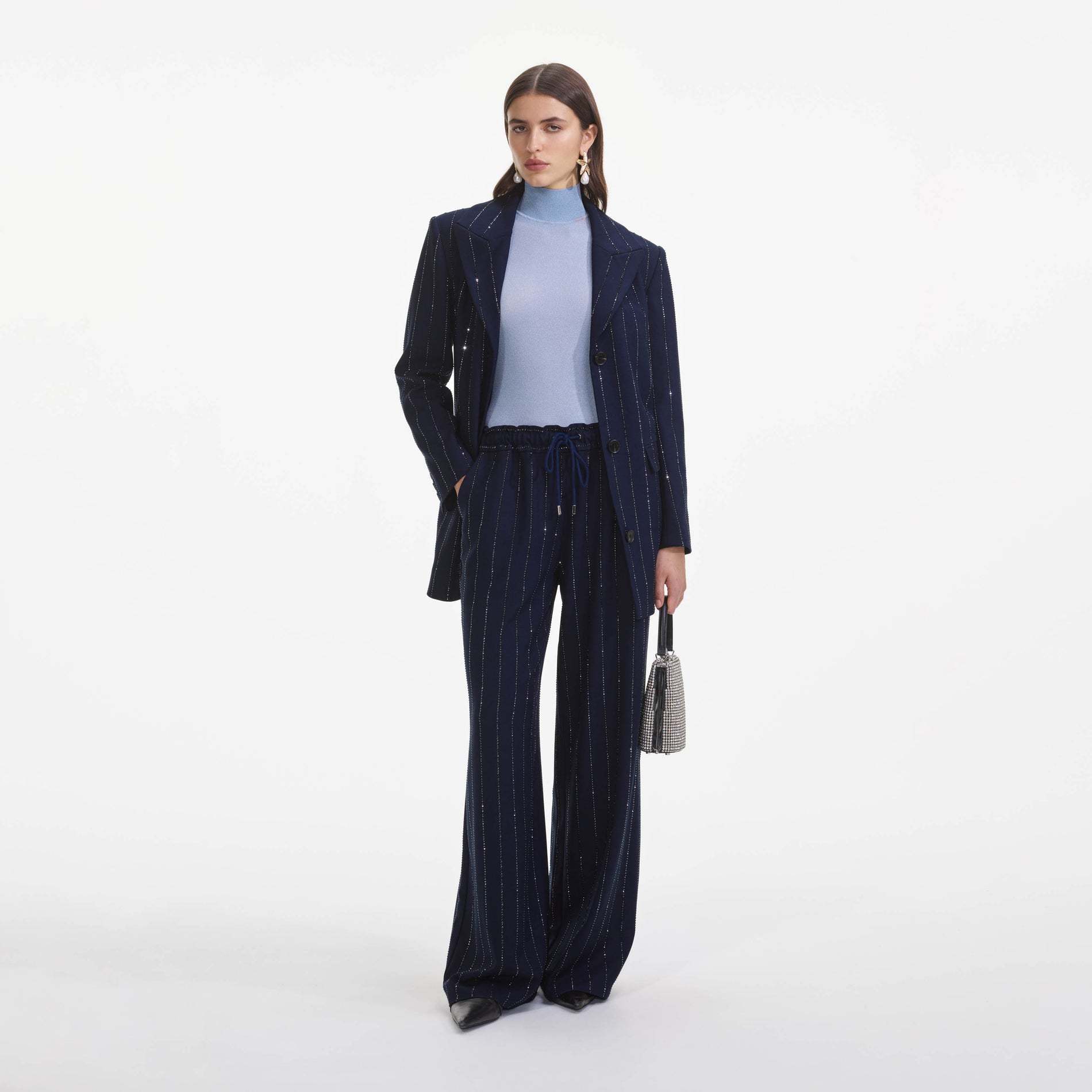 A close up of a woman wearing the Navy Rhinestone Pinstripe Trousers