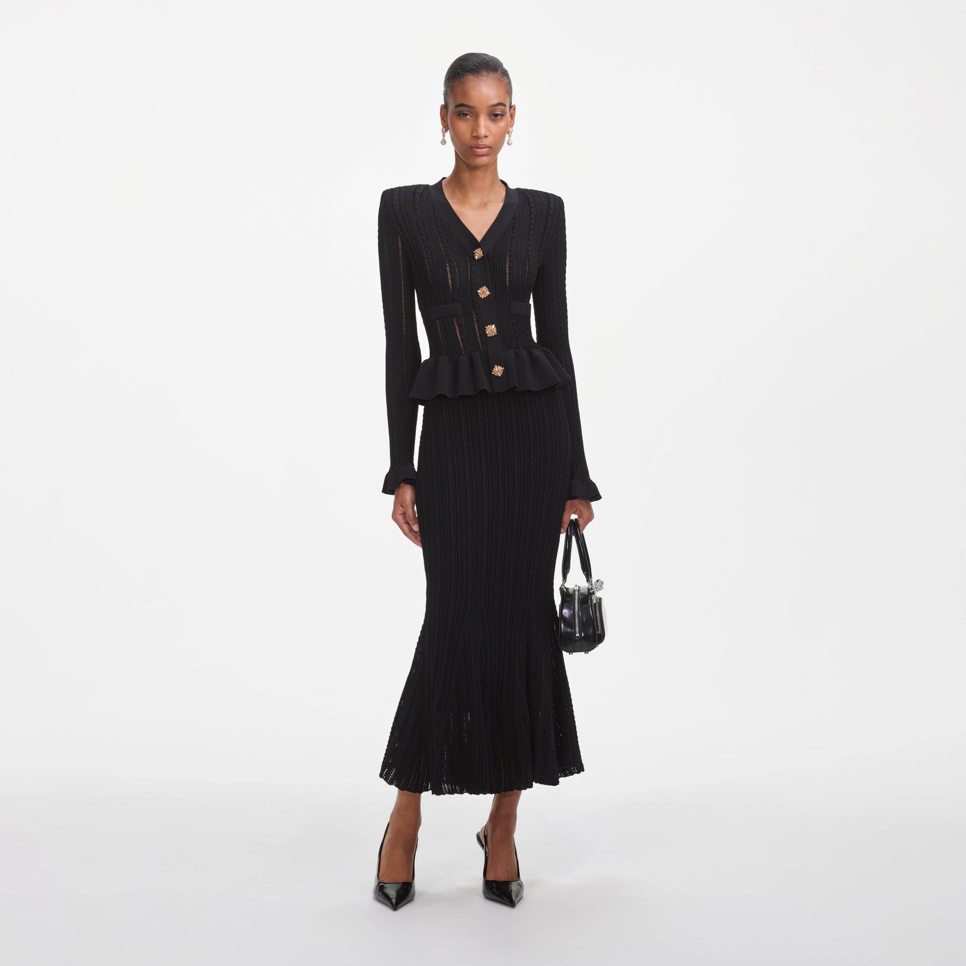 A close up of a woman wearing the Black Knit Peplum Midi Dress