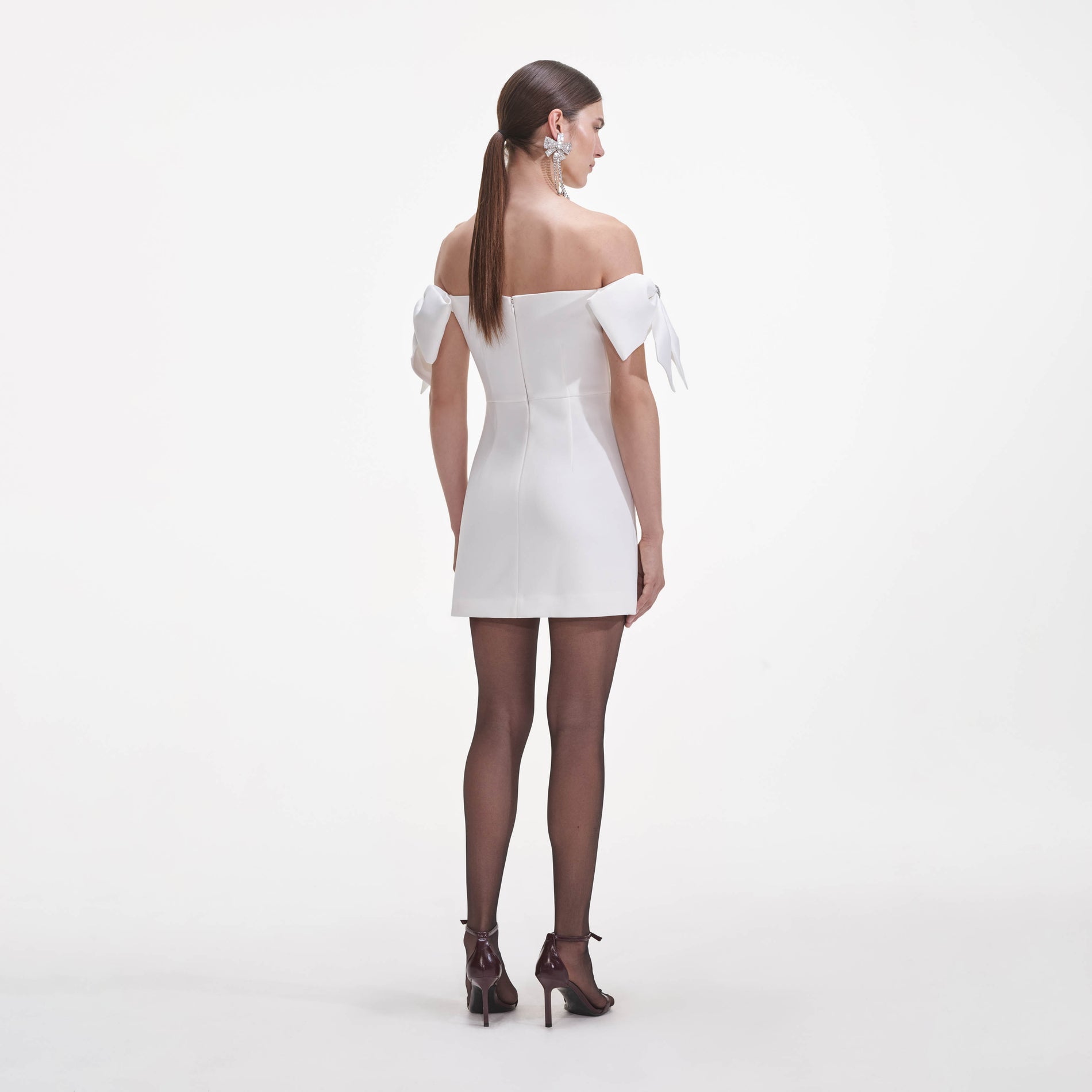 Back view of a woman wearing the White Crepe Bow Mini Dress