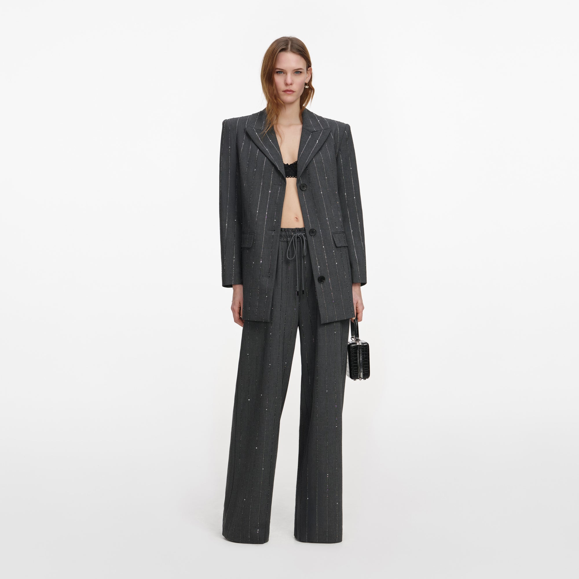 Front view of a woman wearing the Grey Rhinestone Pinstripe Trousers