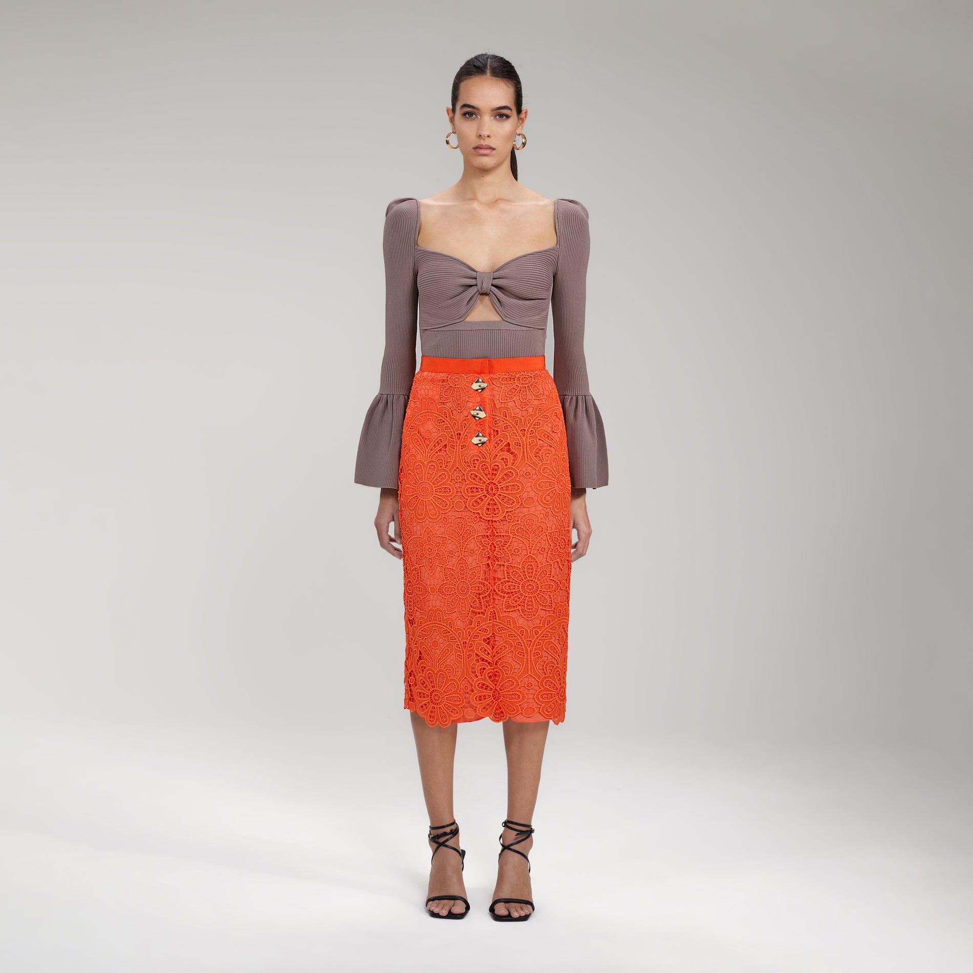 A woman wearing the Orange Floral Guipure Midi Skirt