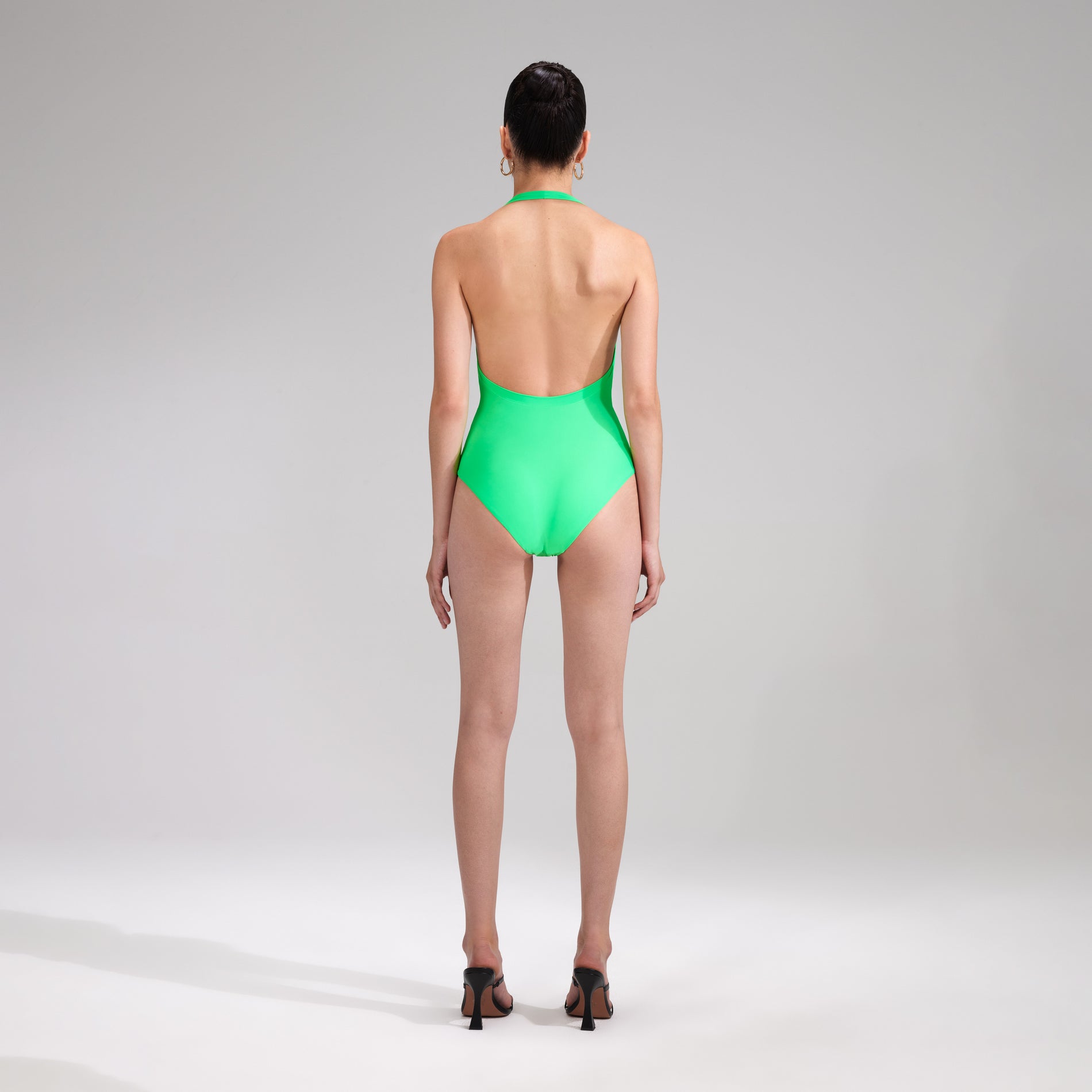 A woman wearing the Green Twist Front Swimsuit
