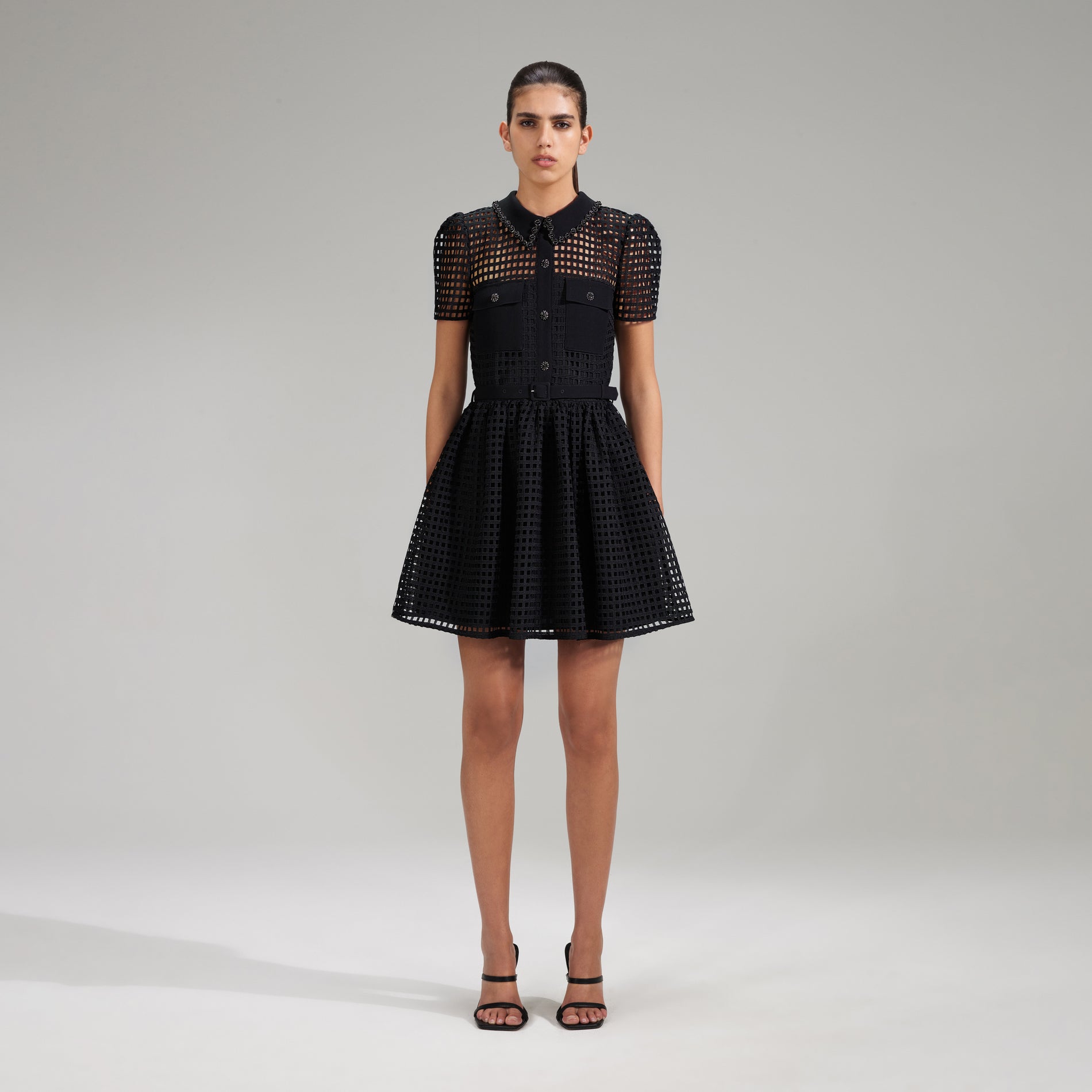 A woman wearing the Black Grid Lace Mini Dress