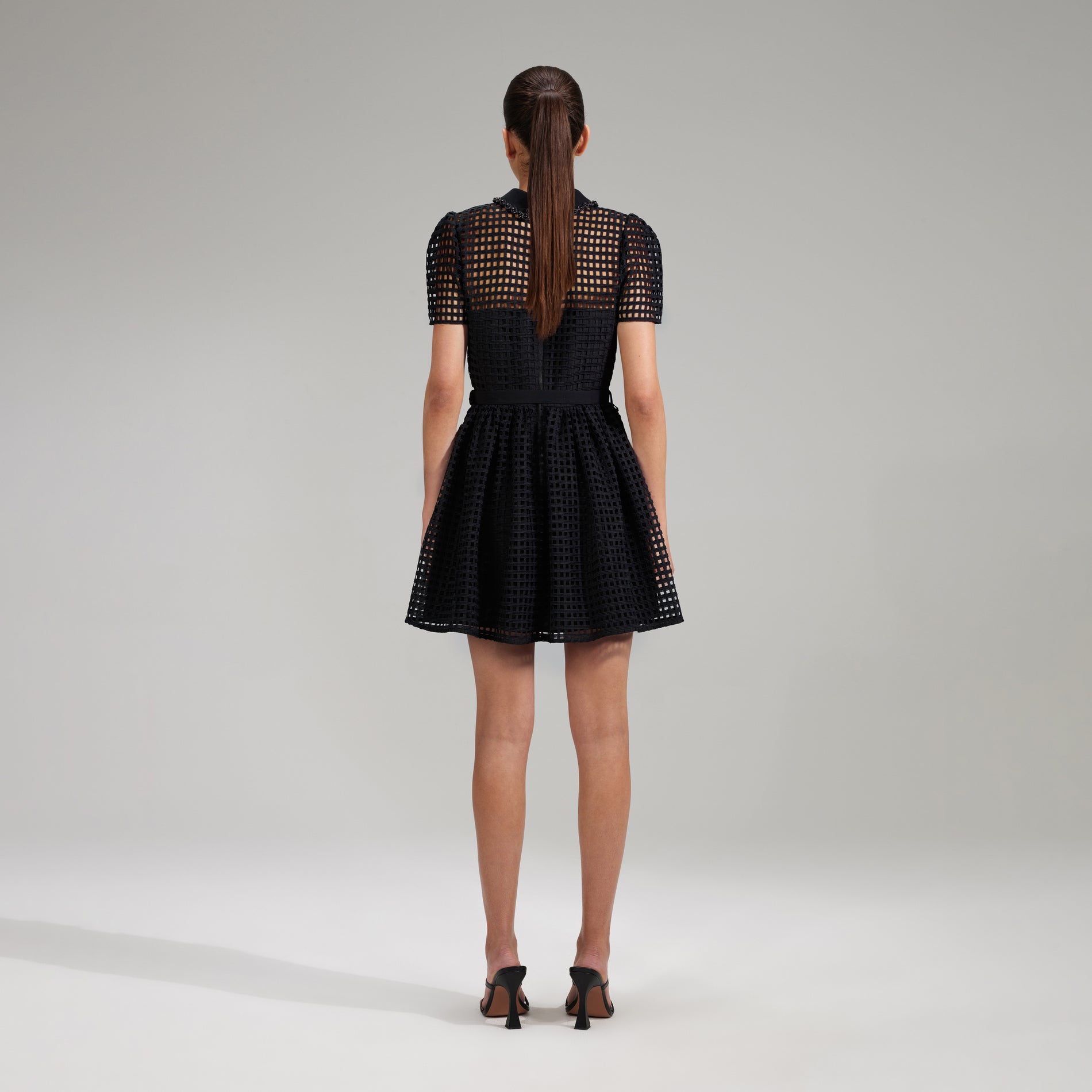 A woman wearing the Black Grid Lace Mini Dress
