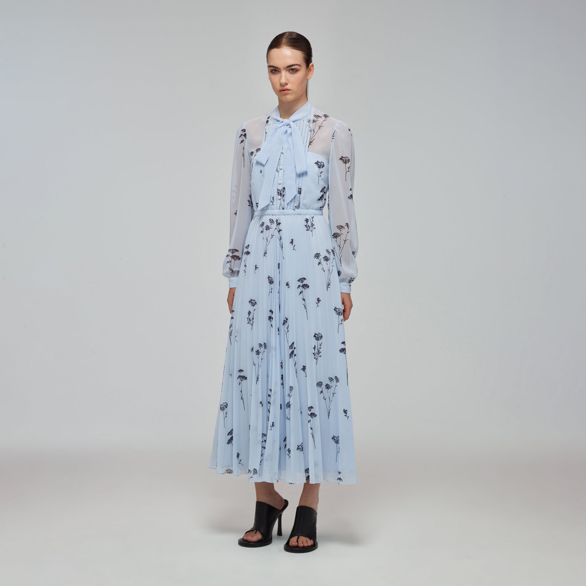 A woman wearing the Blue Floral Silhouette Chiffon Midi Dress