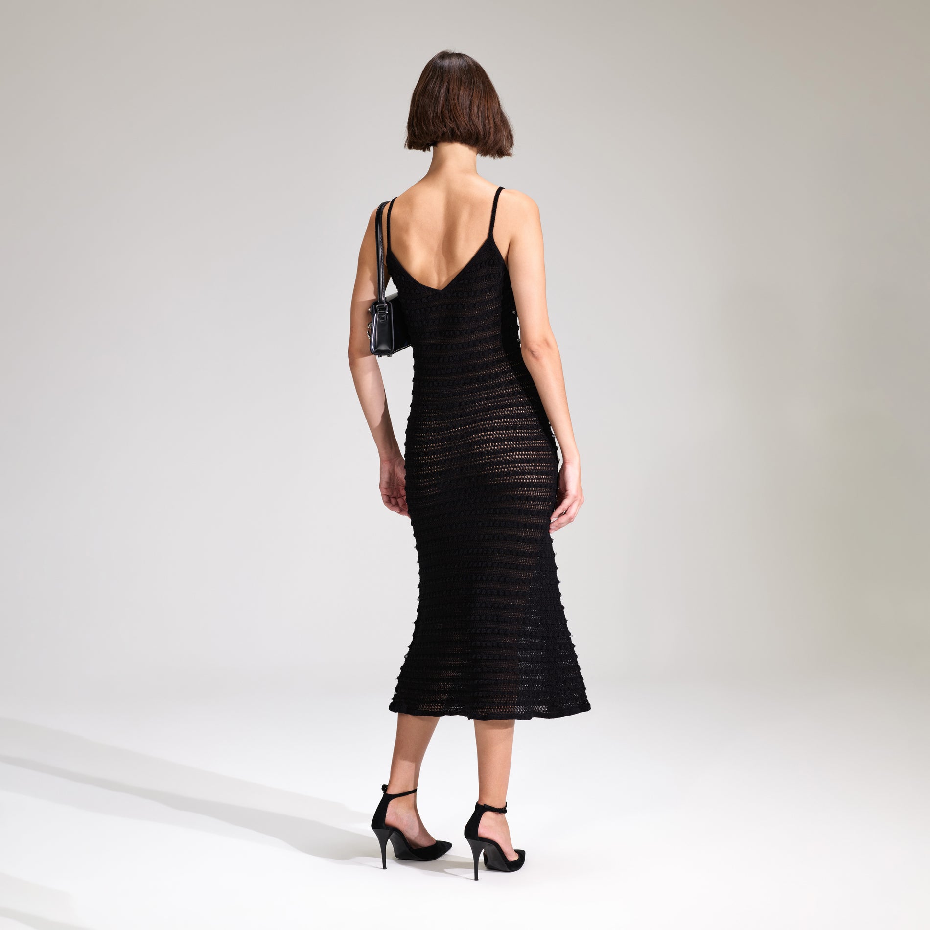 A woman wearing the Black Beaded Strappy Knit Midi Dress